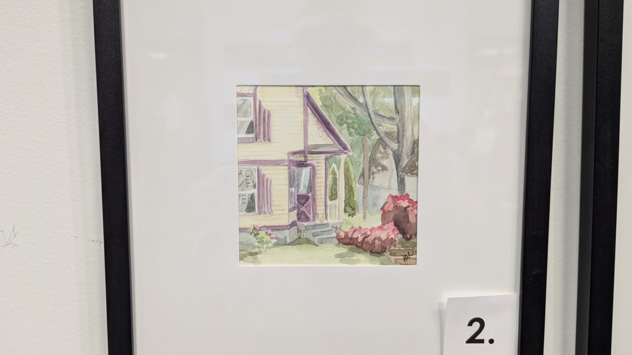 5x5 watercolor painting of a yellow house with BLM markered in a window in a 10x10 frame.
